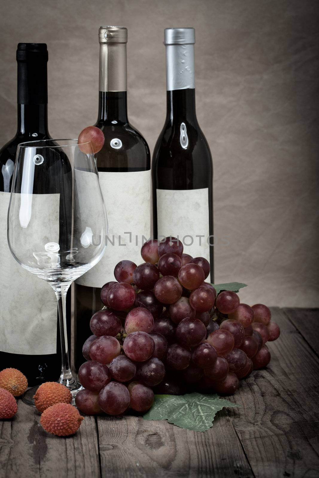 red grapes with wine bottles on wooden background