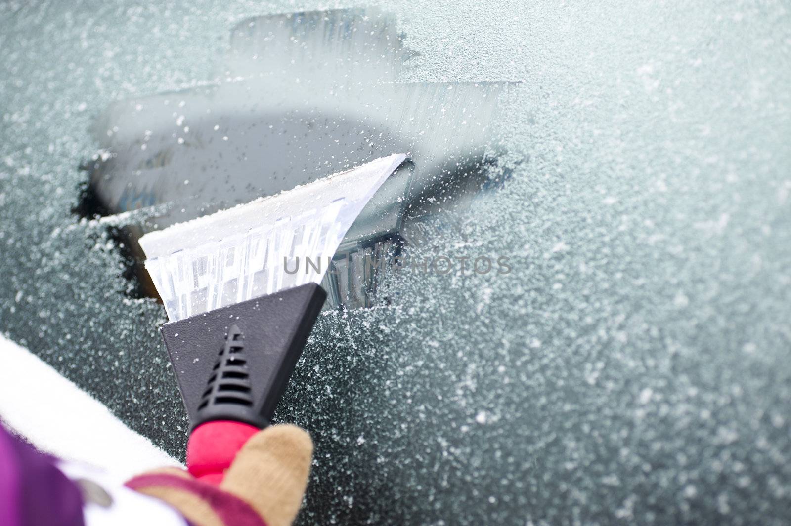 scraping snow and ice from the car windscreen