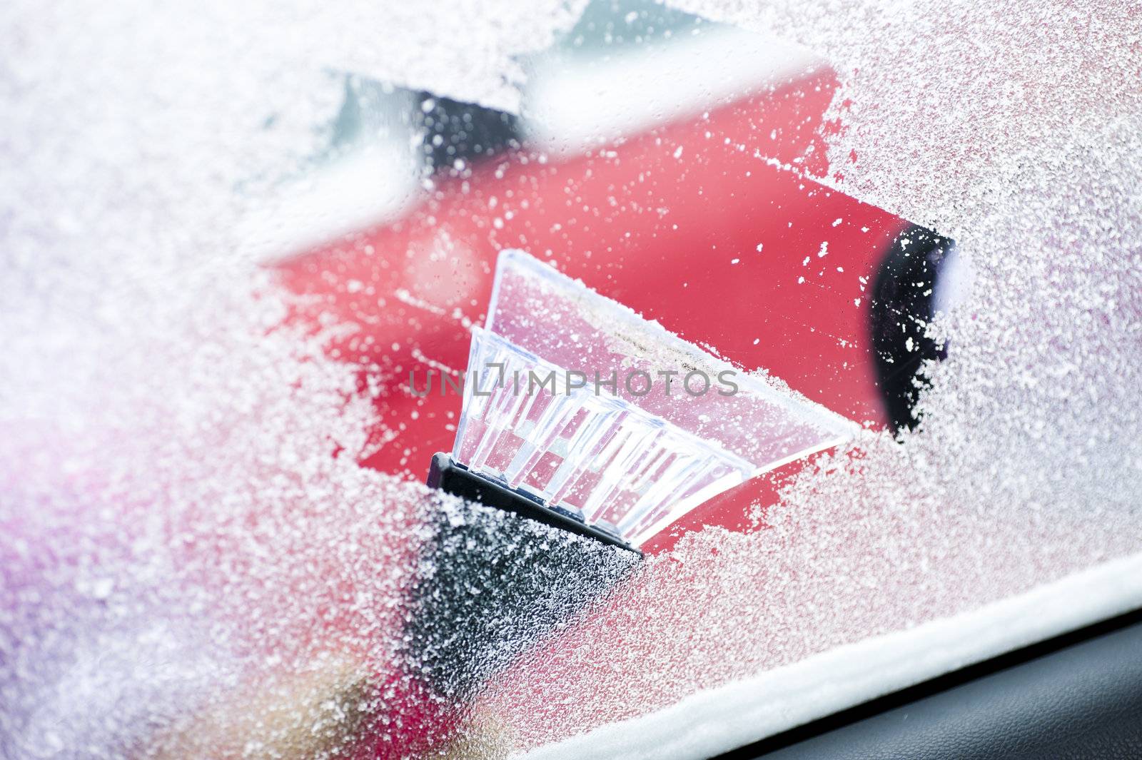 scraping snow and ice from the car windscreen