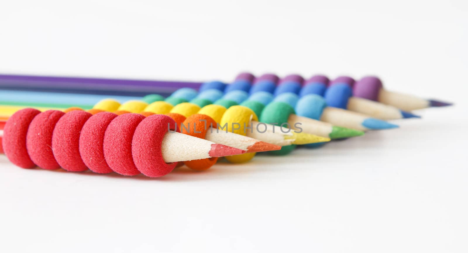 pencils arranged in color order of the rainbow on white background