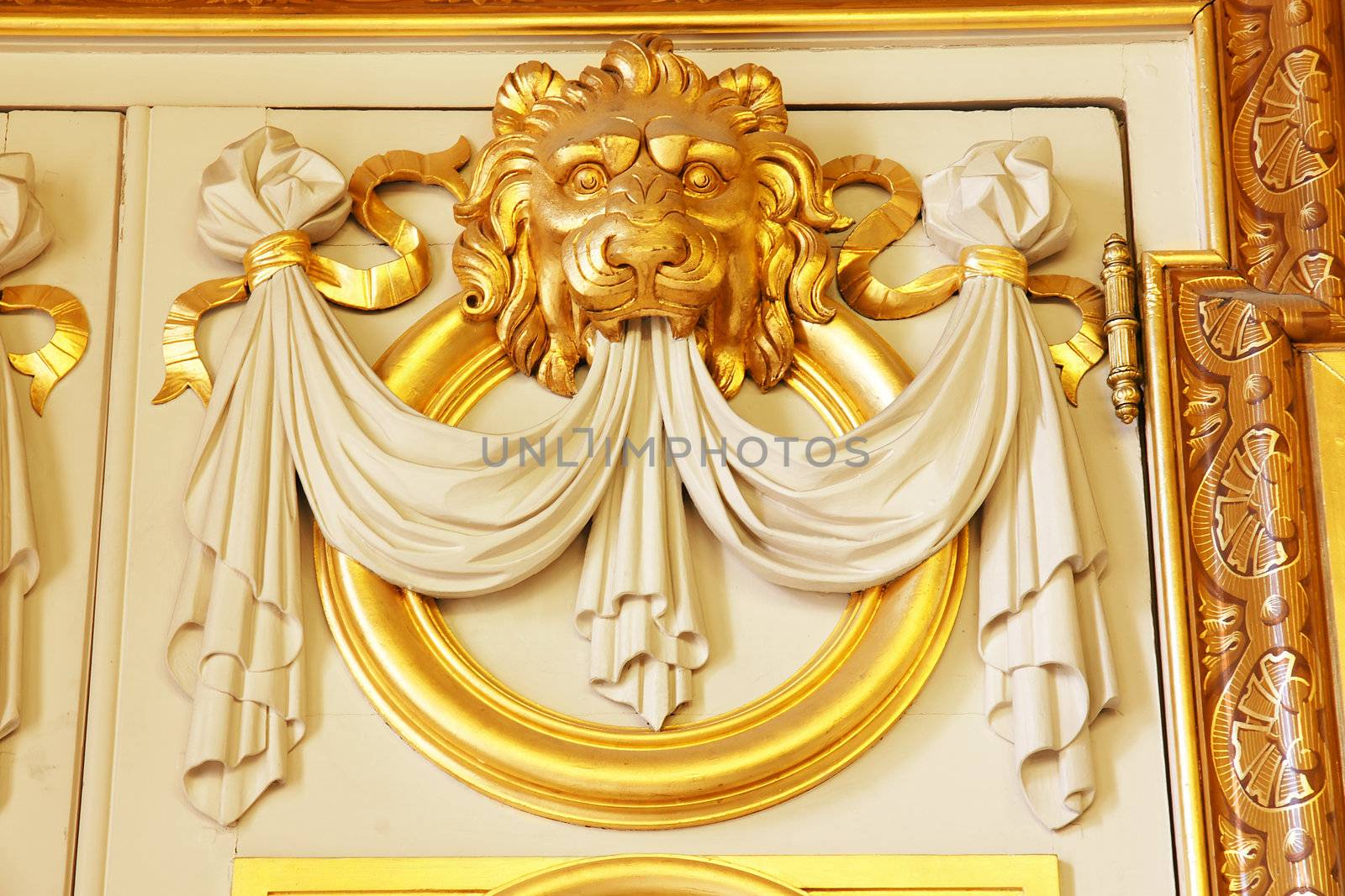 Great architectural detail above a door of an old european historical building of an ornate sculpted gold lion head.