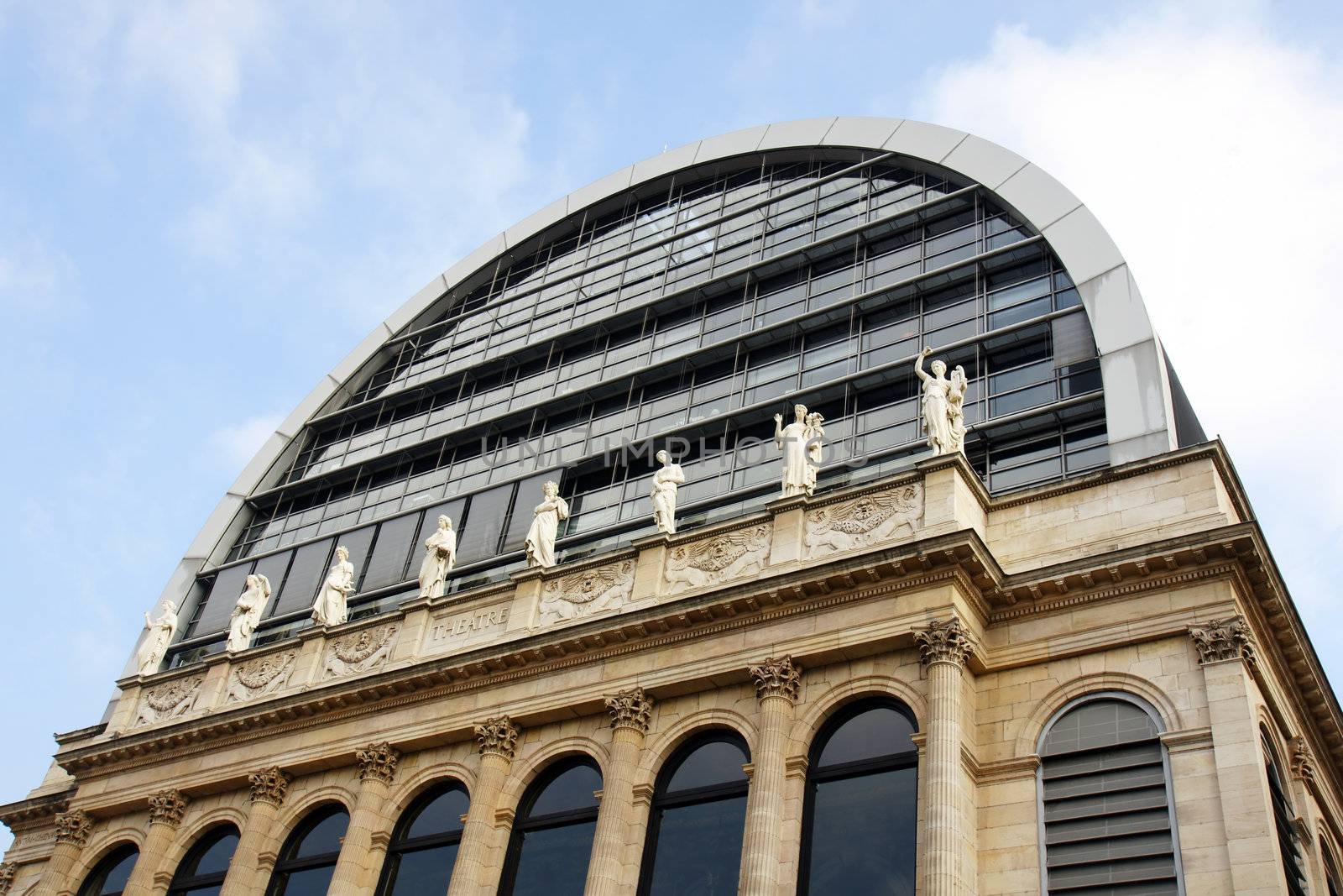 Perspective shot of an opera house with neoclassical architecture and statues mixed with modern dome roof, Lyon, France, historical and touristical landmark.