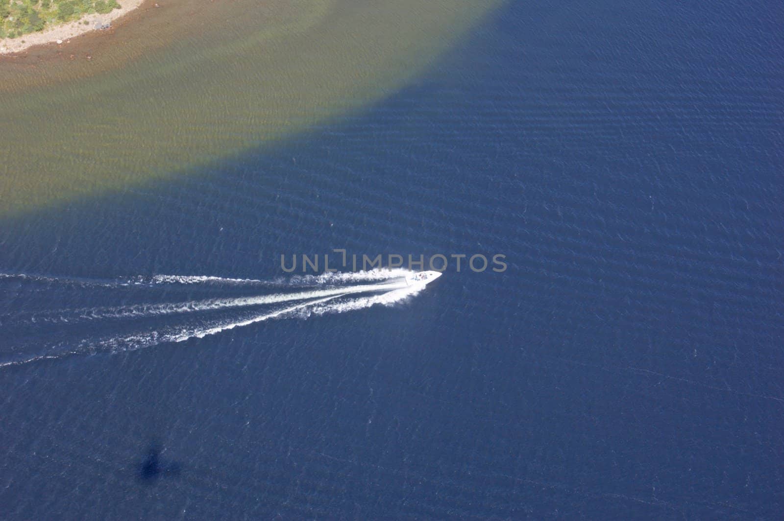 Small boat tracks on surface of water in sunlit