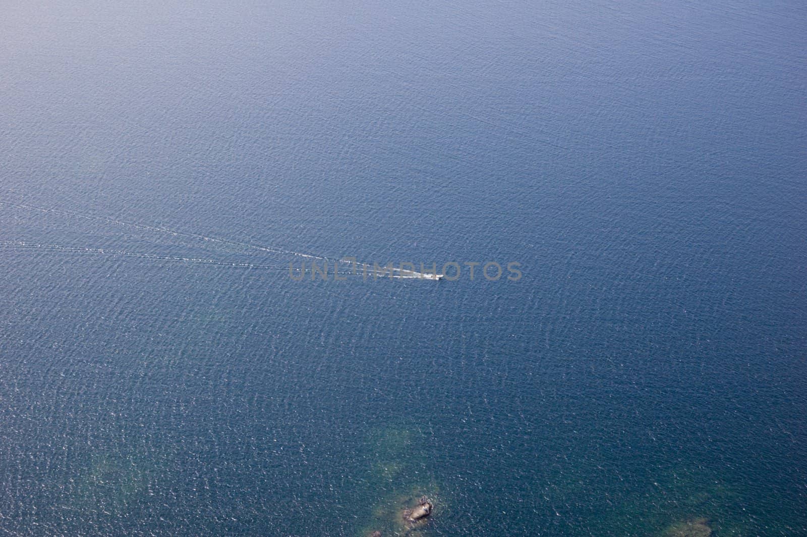 Small boat tracks on surface of water in sunlit
