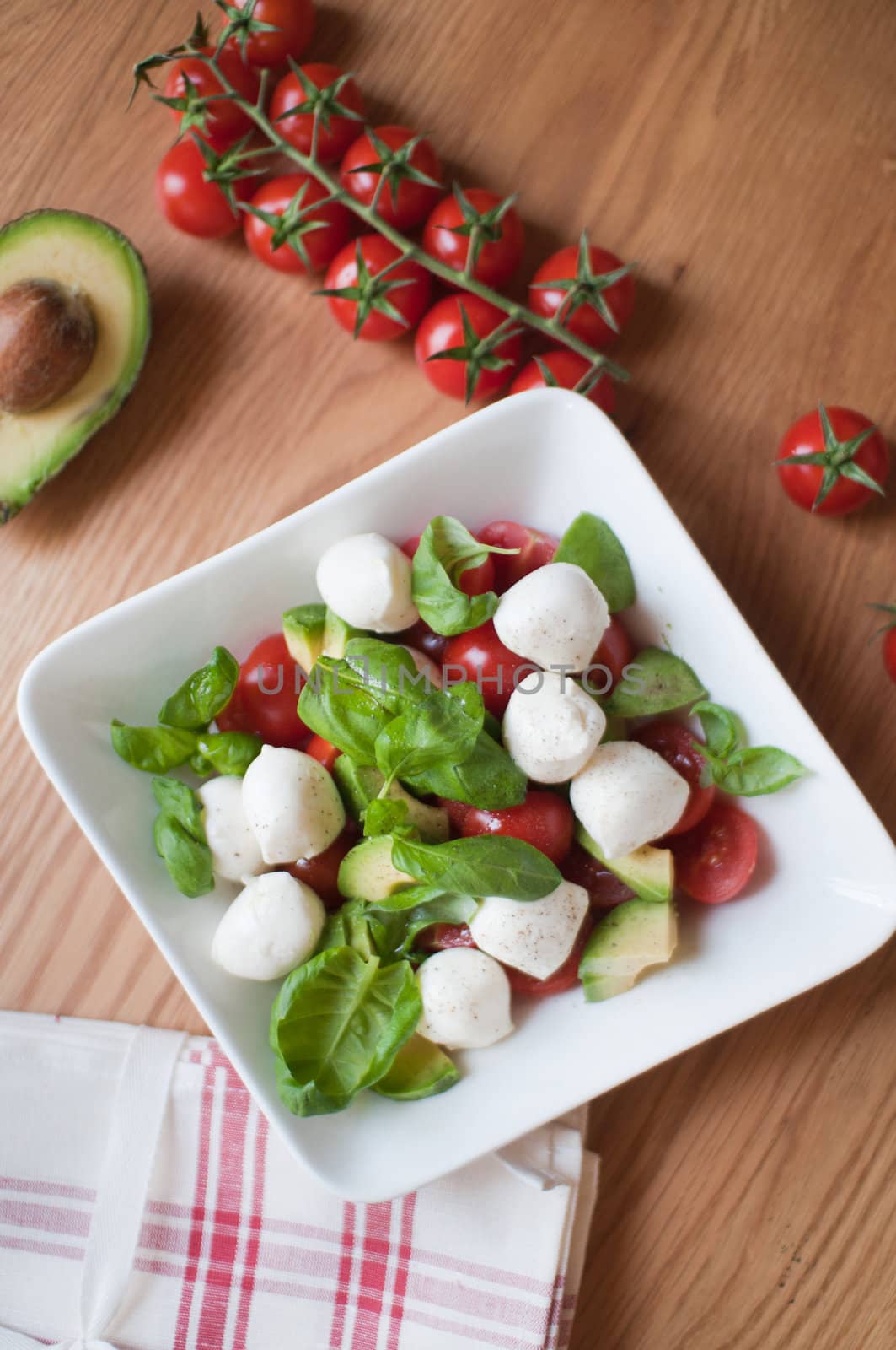 Preparing vegetarian salad from tomatoes, basil and avocado