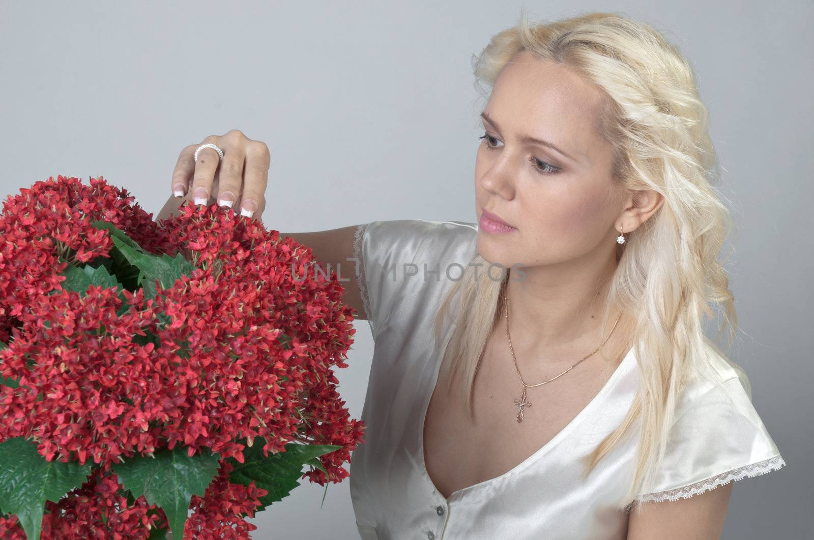 Portrait of a young beautiful girl with a bouquet of red flowers in vase