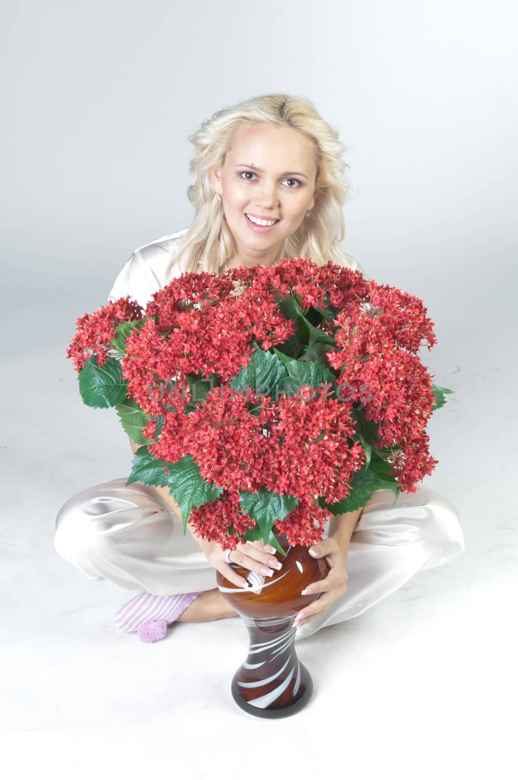 Portrait of a young beautiful girl with a bouquet of red flowers in vase