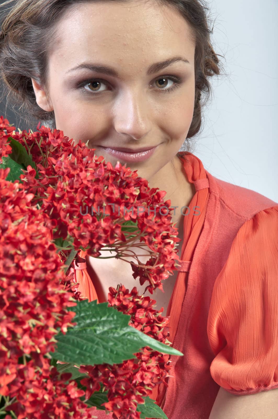 Portrait of a young beautiful girl with a bouquet of red flowers in vase