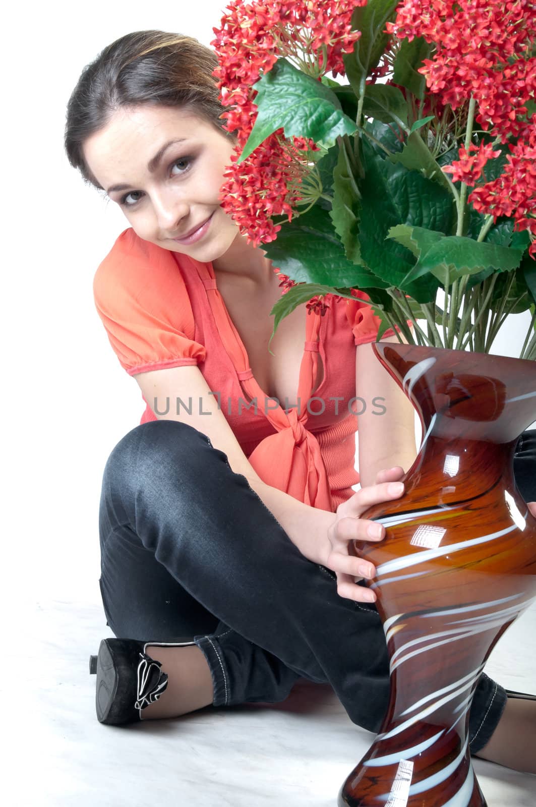 Portrait of a young beautiful girl with a bouquet of red flowers in vase