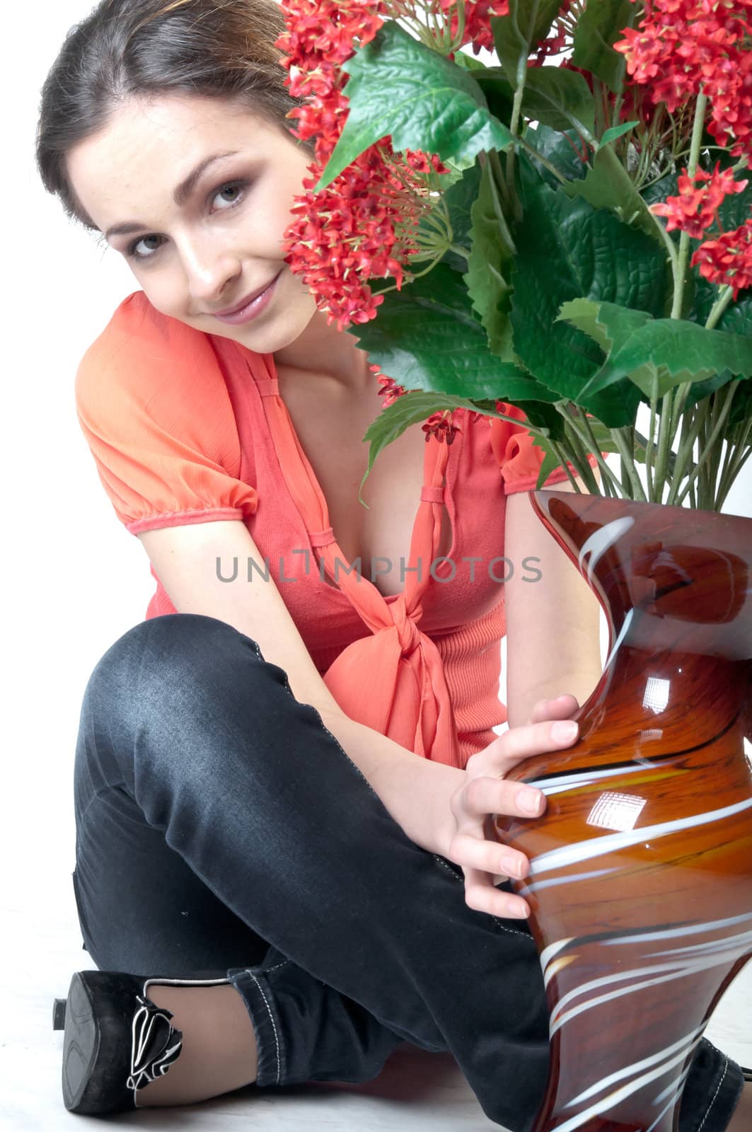 Portrait of a young beautiful girl with a bouquet of red flowers in vase