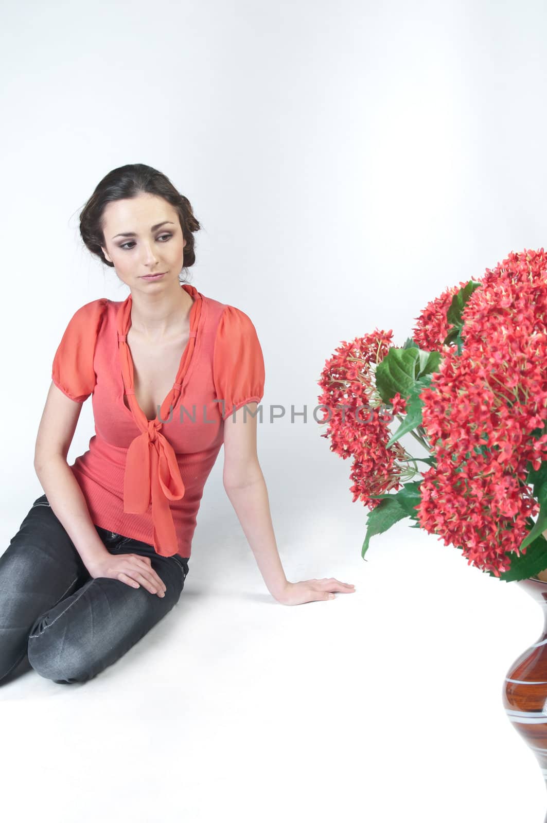 Portrait of a young beautiful girl with a bouquet of red flowers in vase