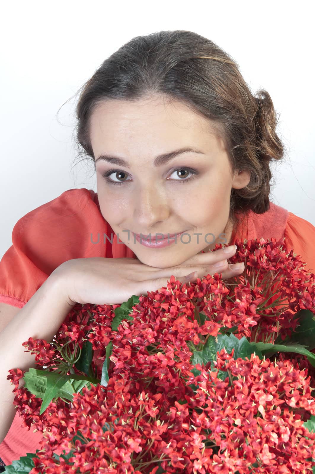 Portrait of a young beautiful girl with a bouquet of red flowers in vase