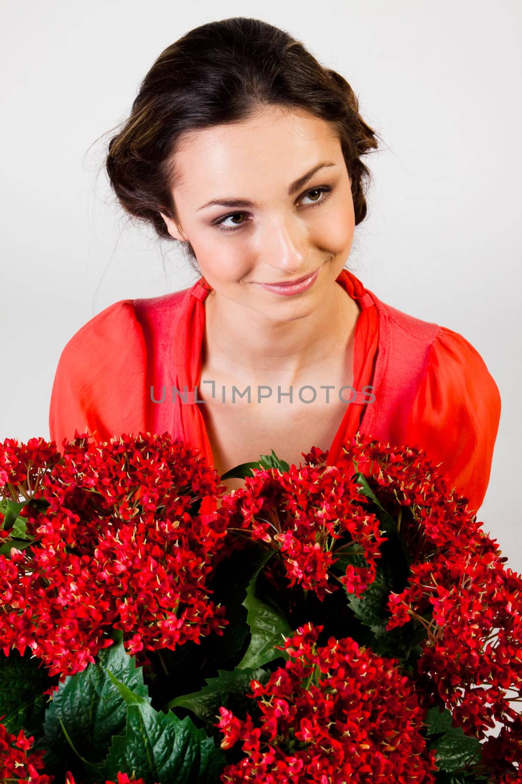 Portrait of a young beautiful girl with a bouquet of red flowers in vase