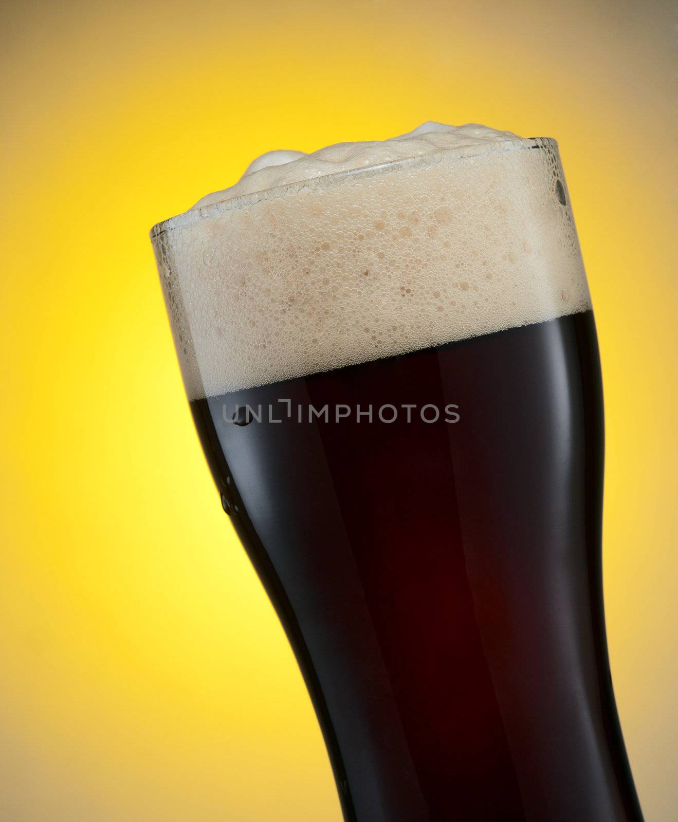Glass of dark beer over yellow background