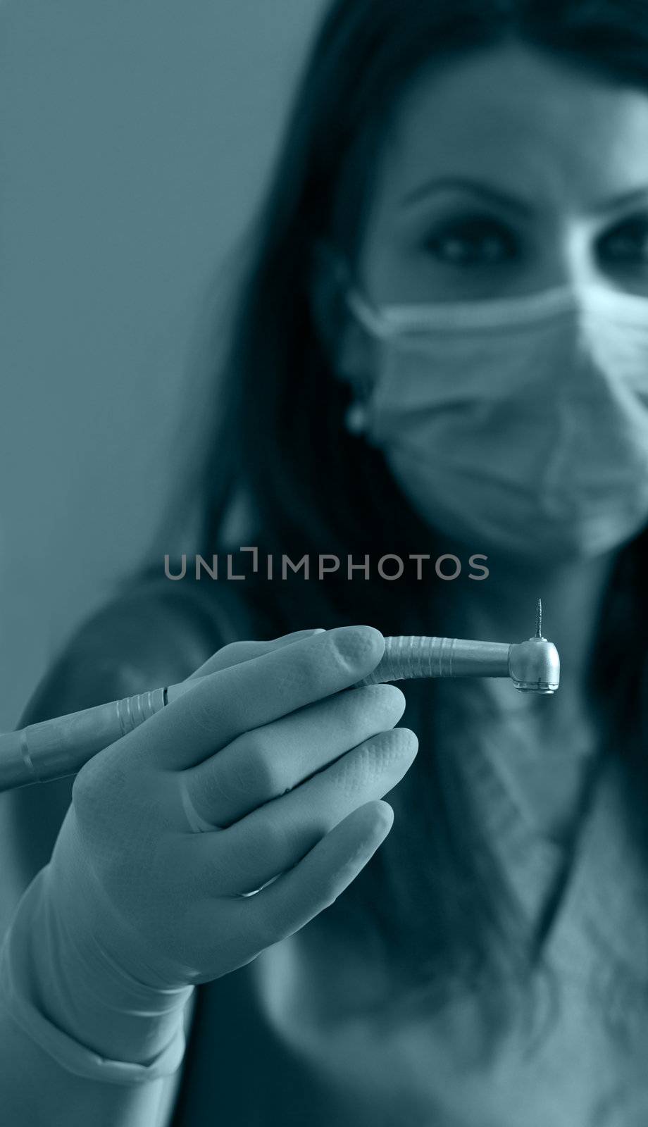Image of a dentist woman holding a drill. Selective focus on the drill.