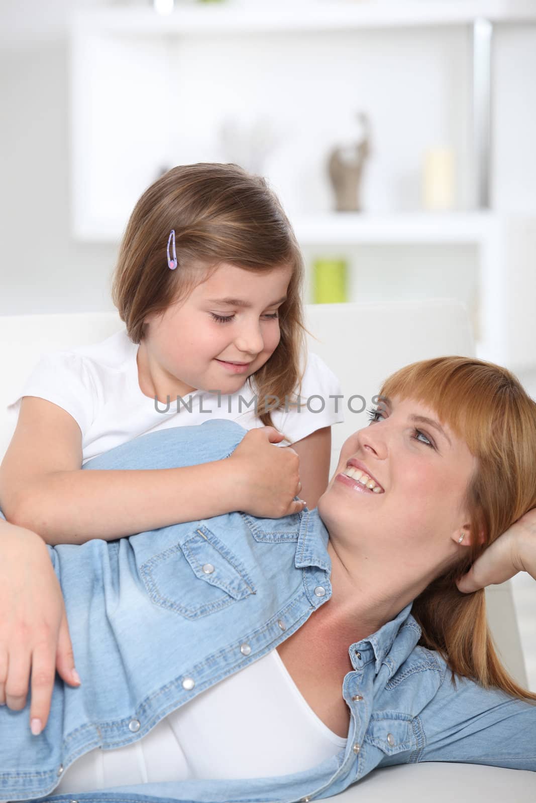 Mother and daughter sat on couch by phovoir