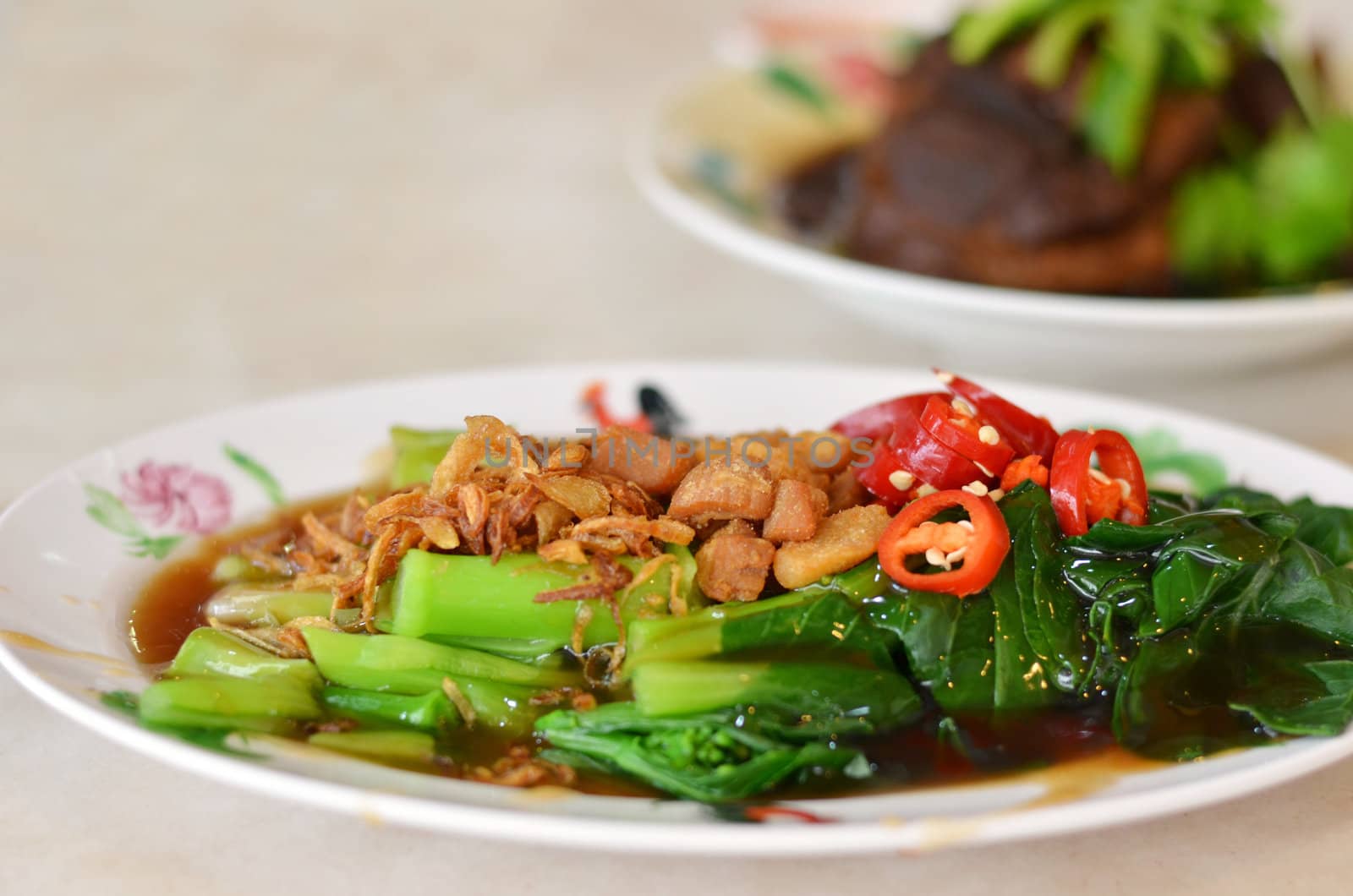 kale fried with oyster sauce  , topped with fried onion and red chili .