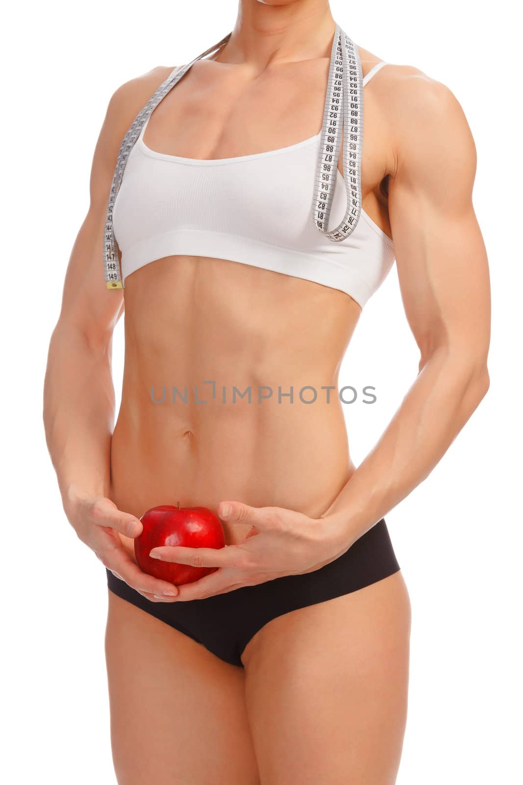 Muscular woman with apple and tape measure posing against white background