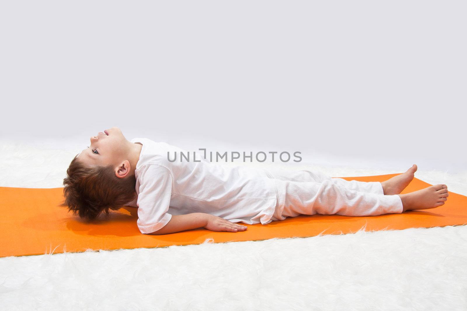 Children's yoga. The little boy does exercise. by NickNick