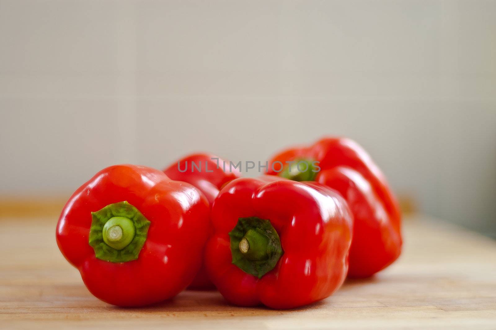 a shallow depth of field image of four organic red peppers on a chopping board
