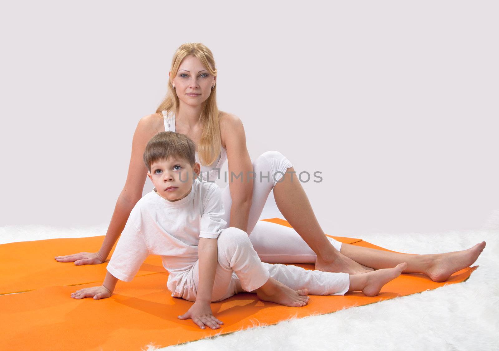 A beautiful young mother practices yoga with her son 