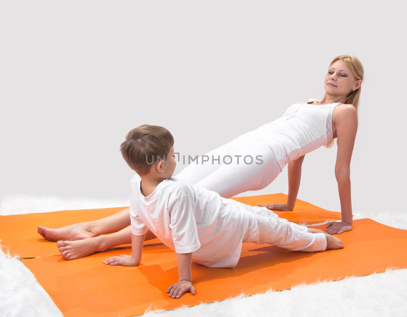 A beautiful young mother practices yoga with her son 