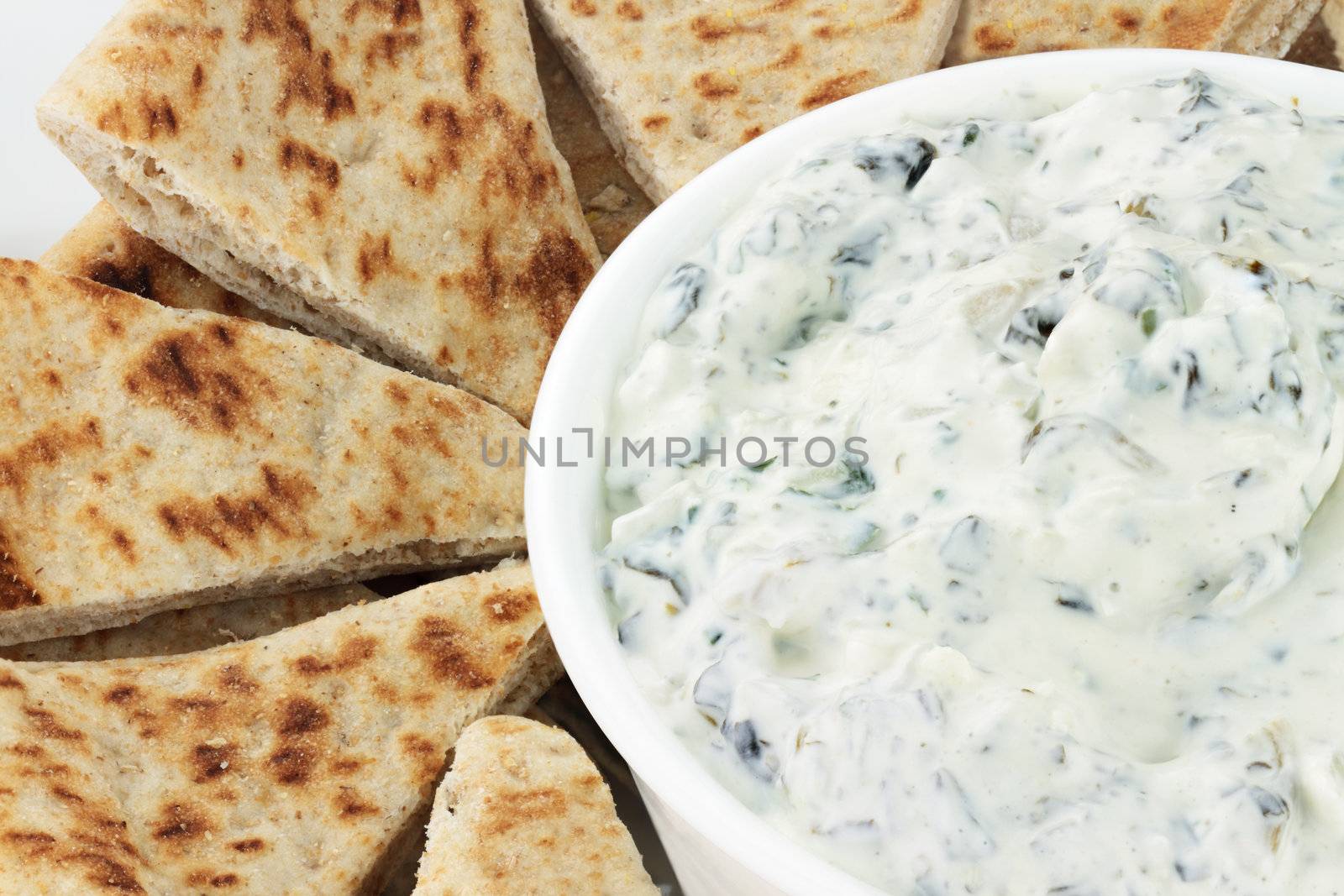 Bowl of fresh vegetarian spinach dip served with wedges of pita bread for a healthy snack. 
