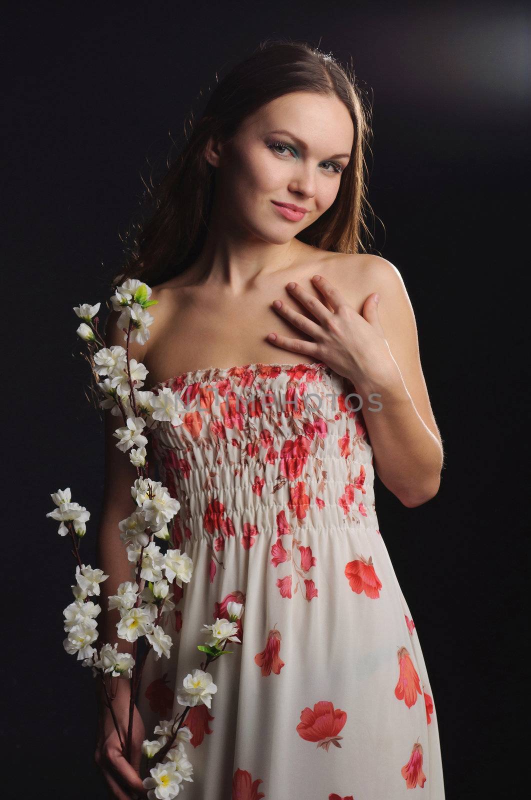 Portrait of a dreamy woman holding sakura in hands. Photograph with little glare of light.