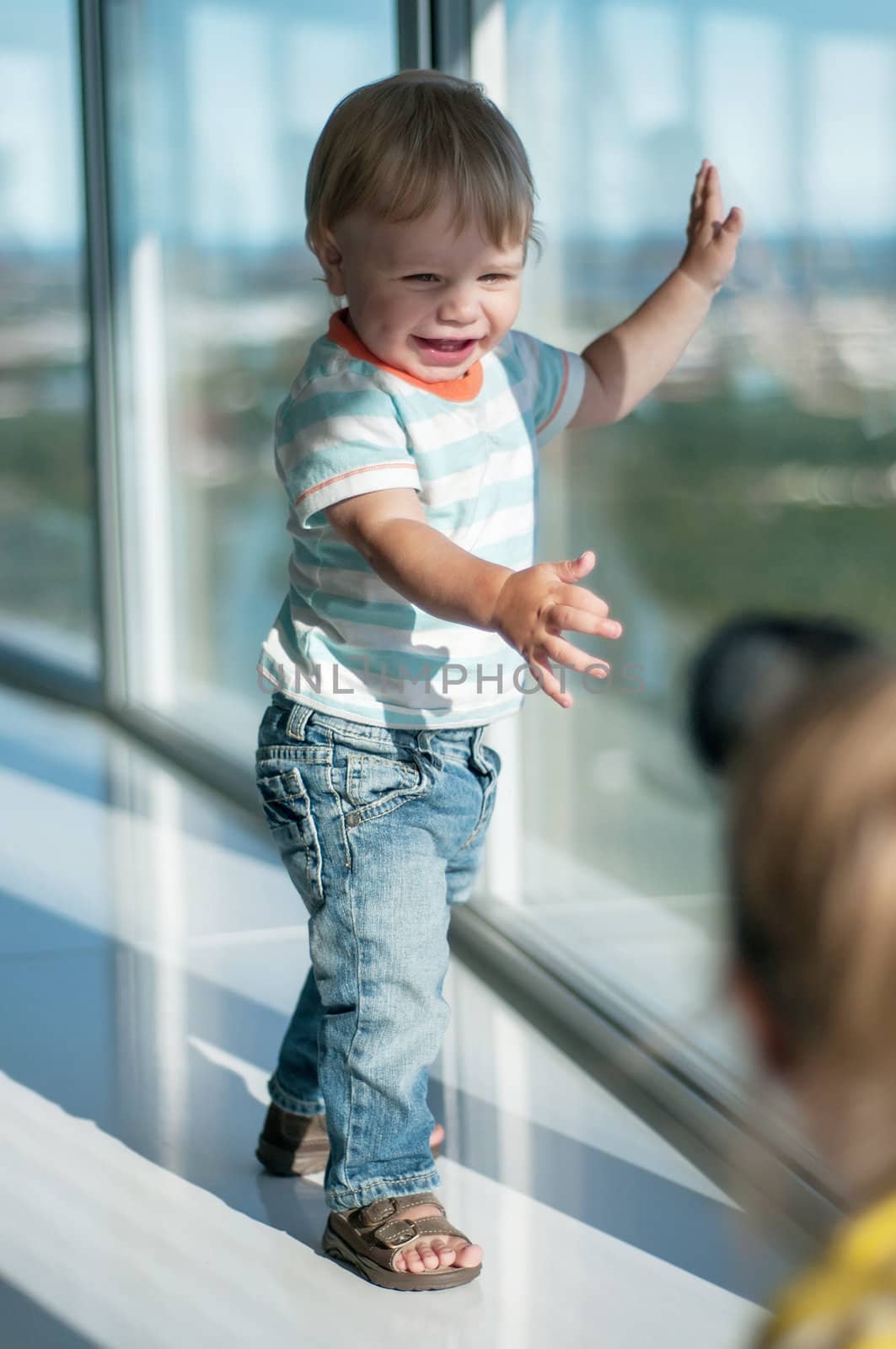 Happy baby boy standing on the windowsill