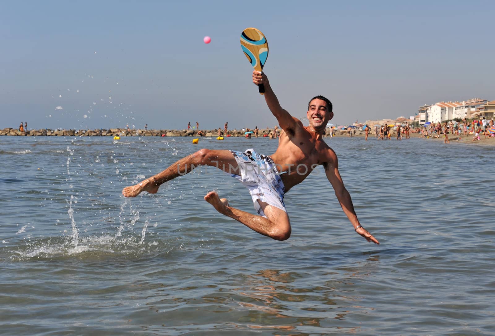 young man playing beach tennis in the sea