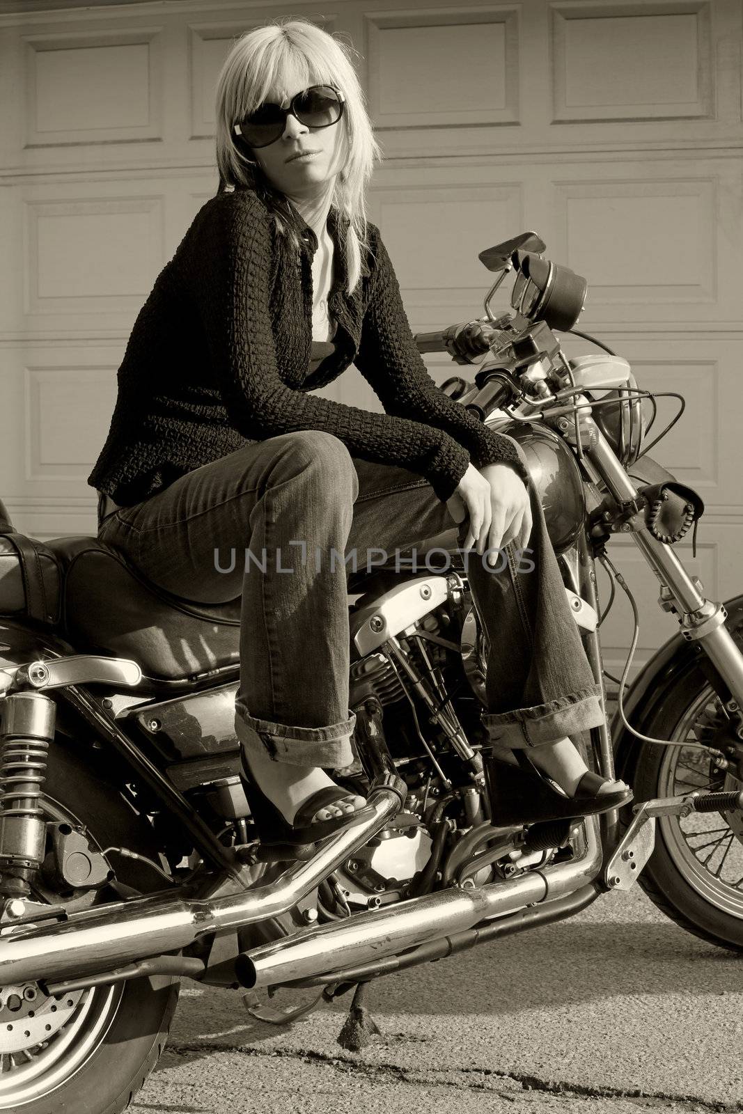 A beautiful blonde female sitting on a motorcycle.
