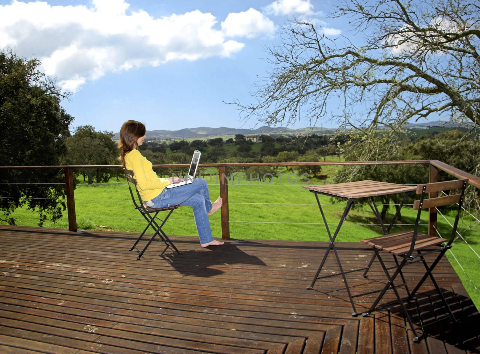 Woman enjoying a beautiful day with a laptop on her home-field