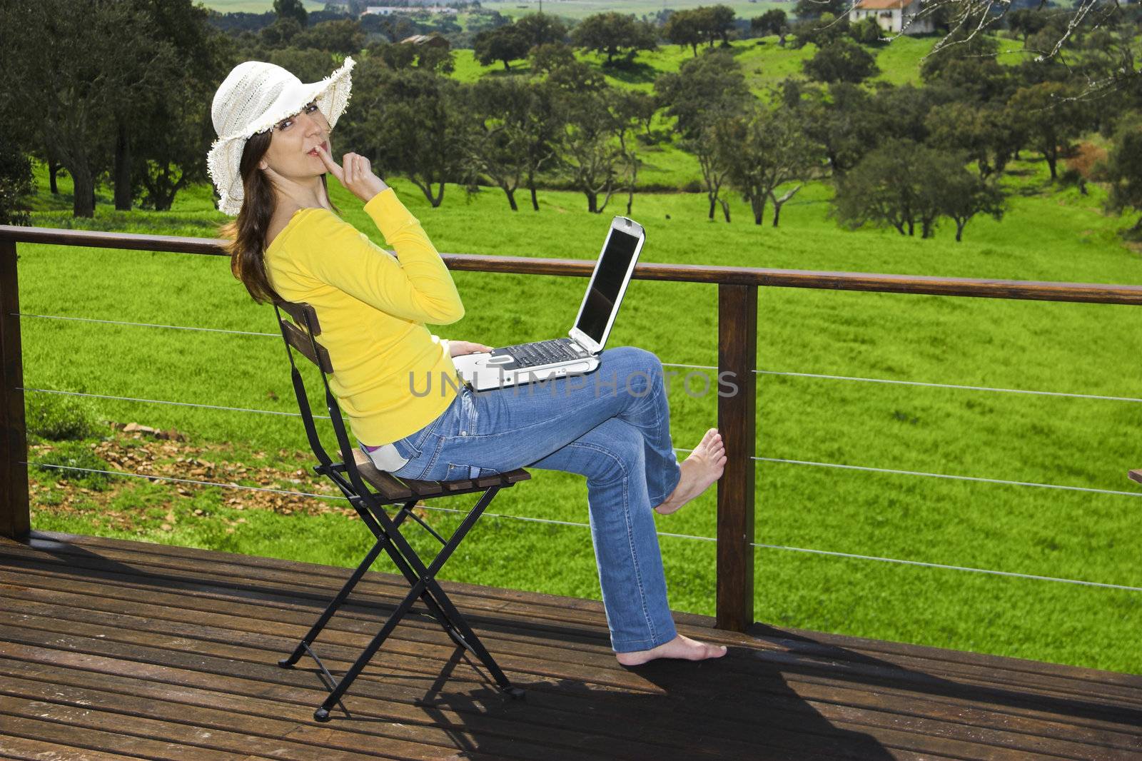 Woman enjoying a beautiful day with a laptop on her home-field