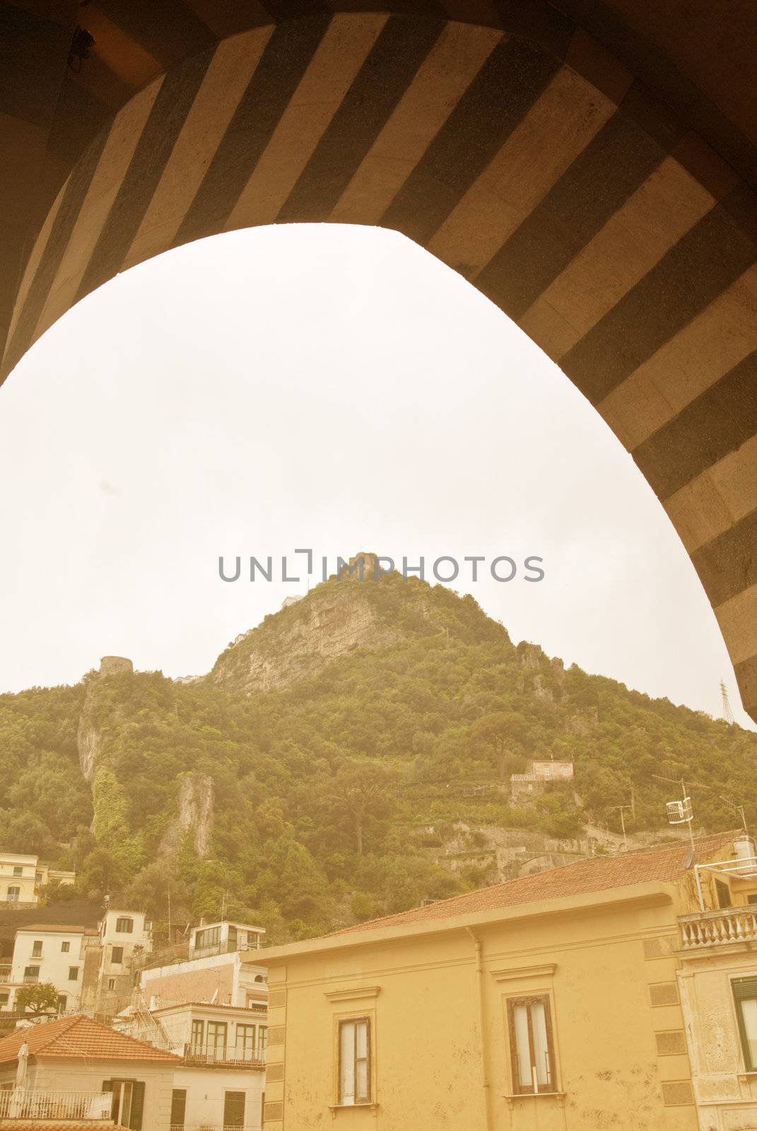 looking through decorative arch to house on top of hill amalfi