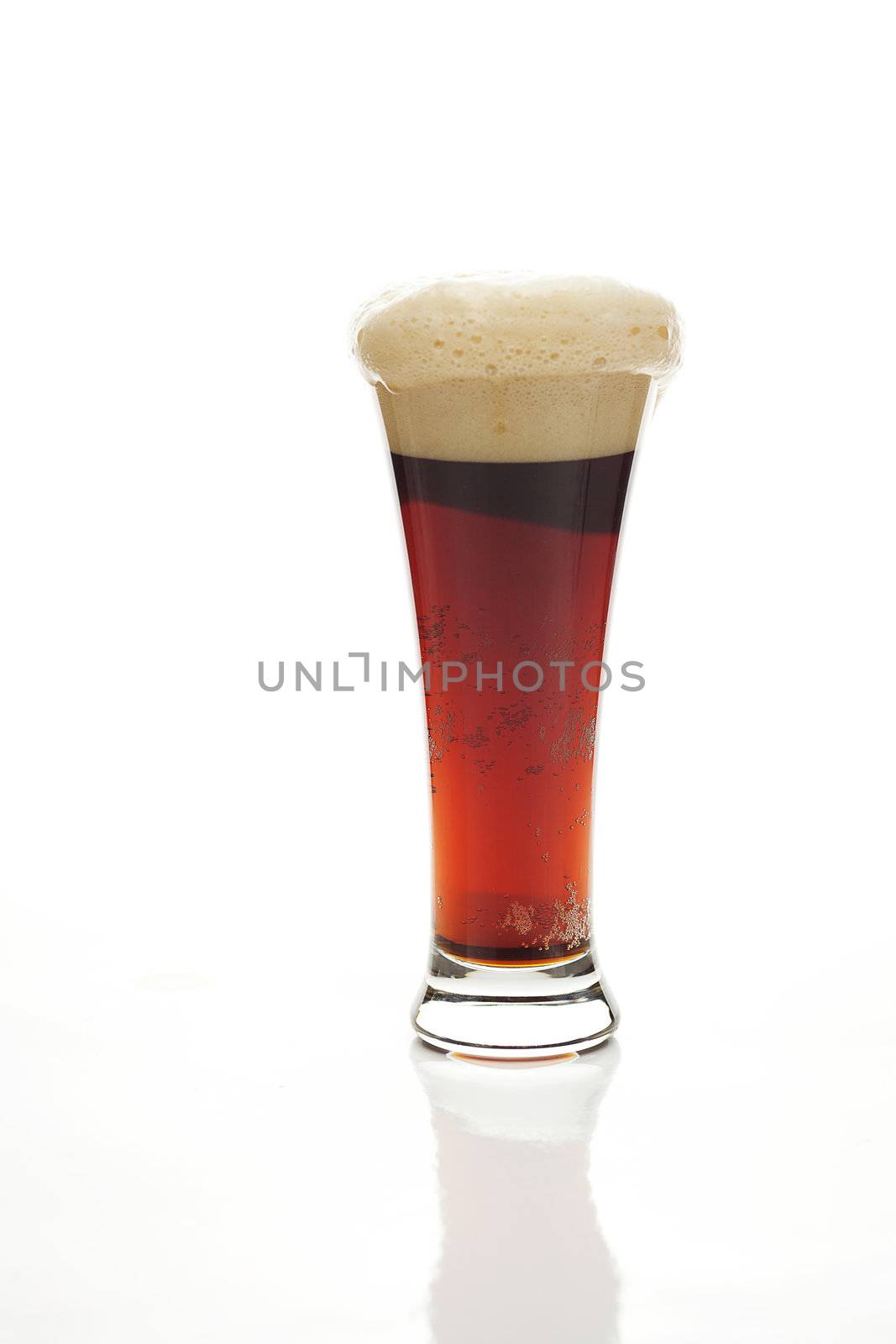 dark beer with the foam in a tall glass isolated on white