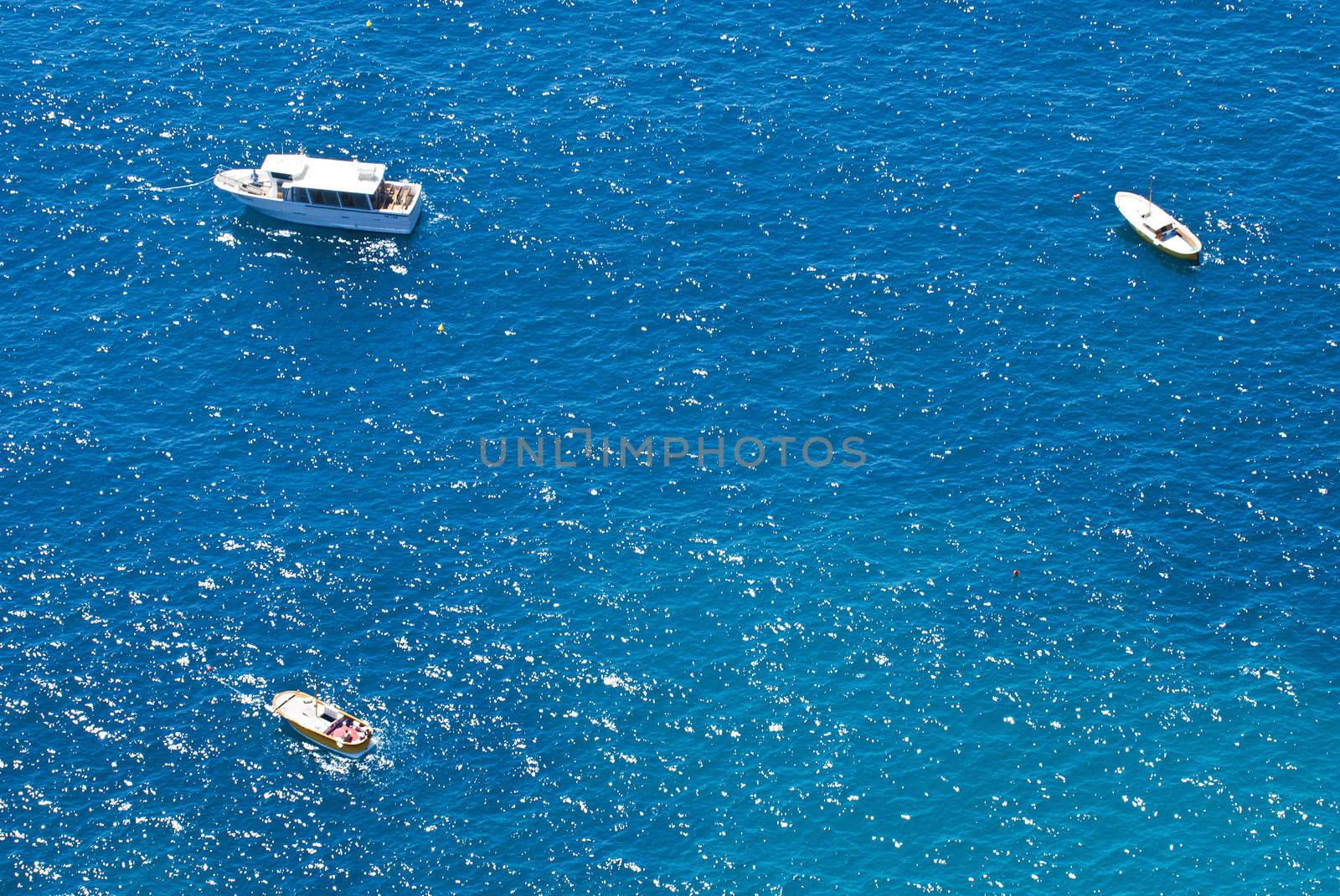 looking down on 3 small boats floating on glistening turqoise sea