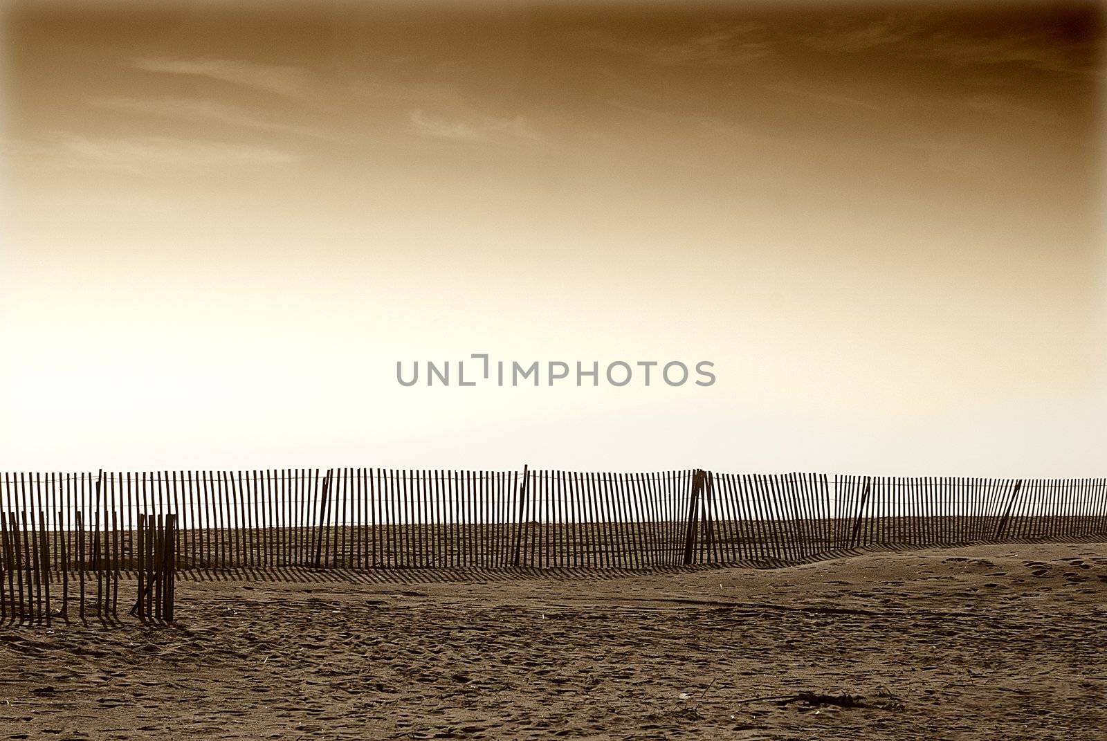 wooden fence along california sandy beach with sepia brown skies