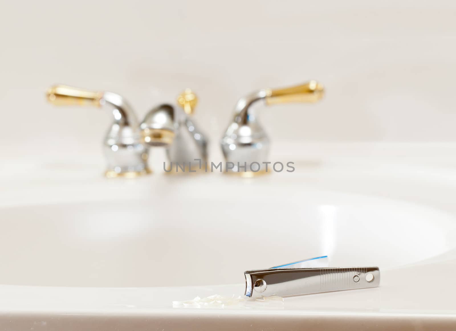 Finger nail clippings on bathroom sink with gold faucets or taps