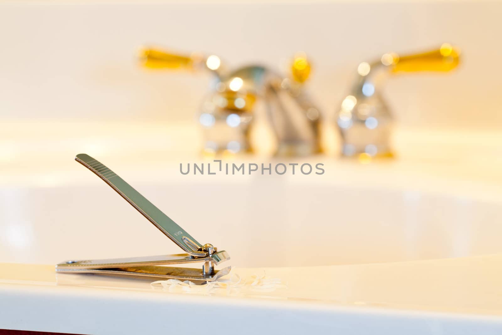 Finger nail clippings on bathroom sink with gold faucets or taps