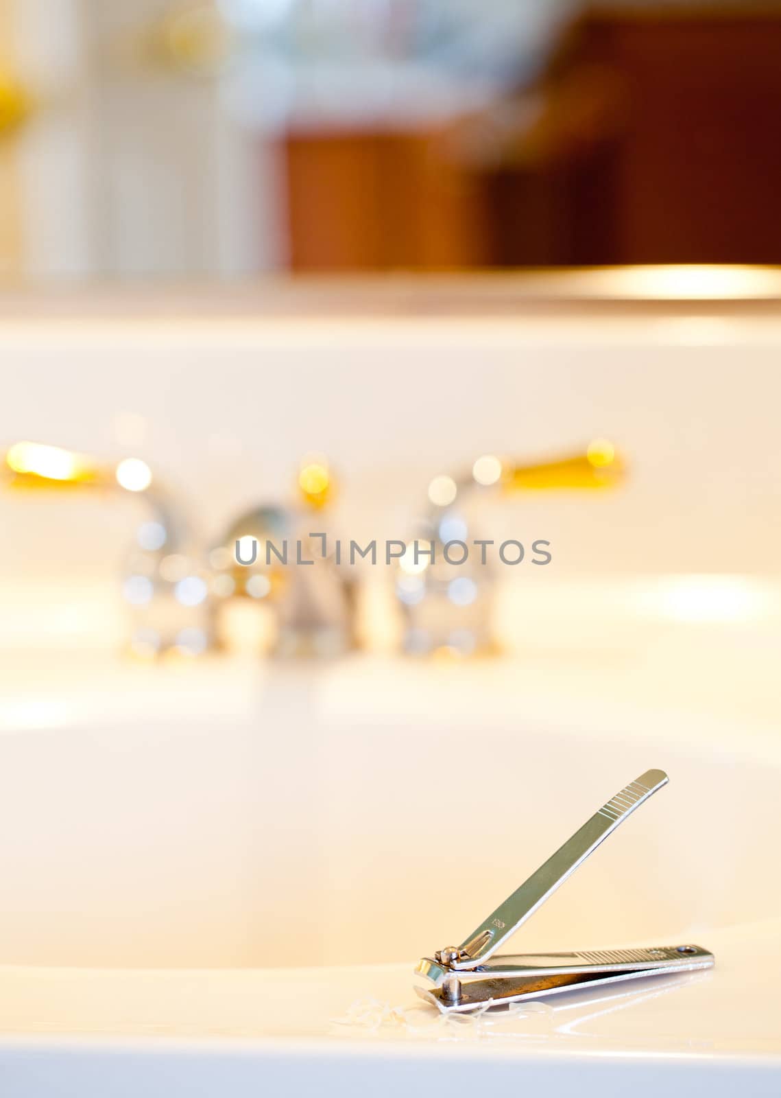 Finger nail clippings on bathroom sink with gold faucets or taps