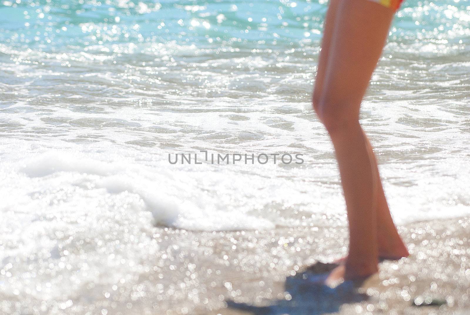 legs of a small boy walking through surf