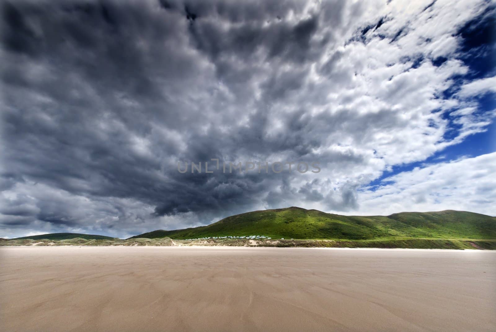 moody skies over deserted yellow sandy beach, gower wales by itsrich