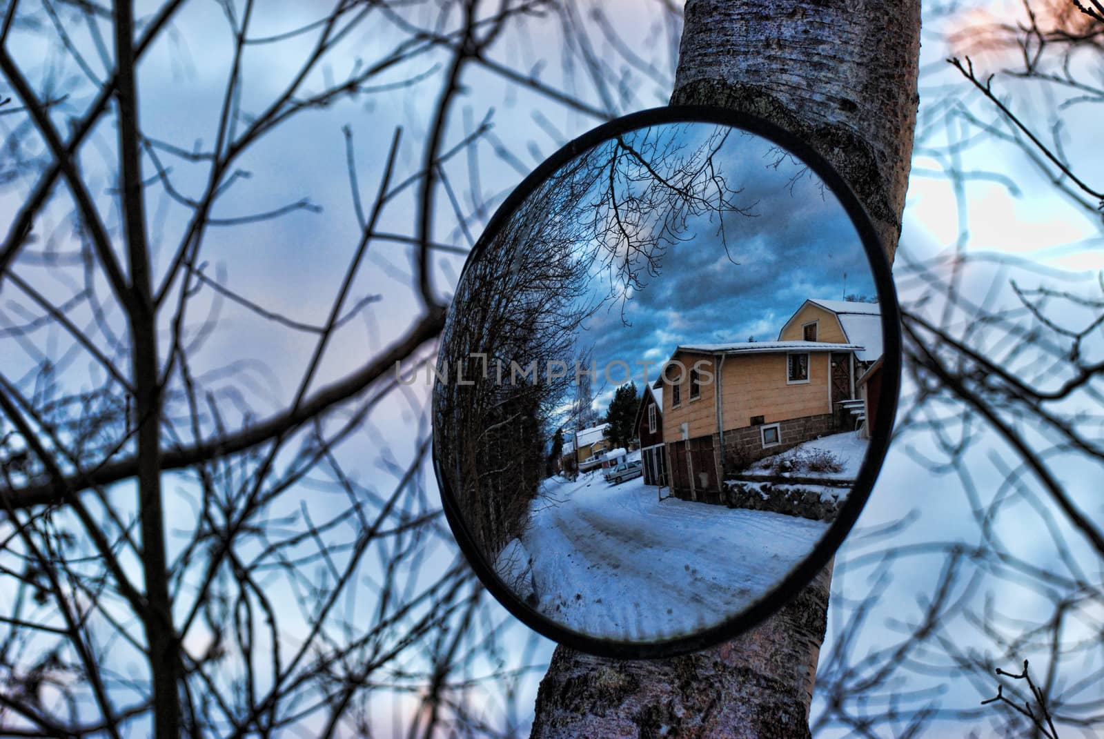 Traffic mirror with a mirror image of a street and a house