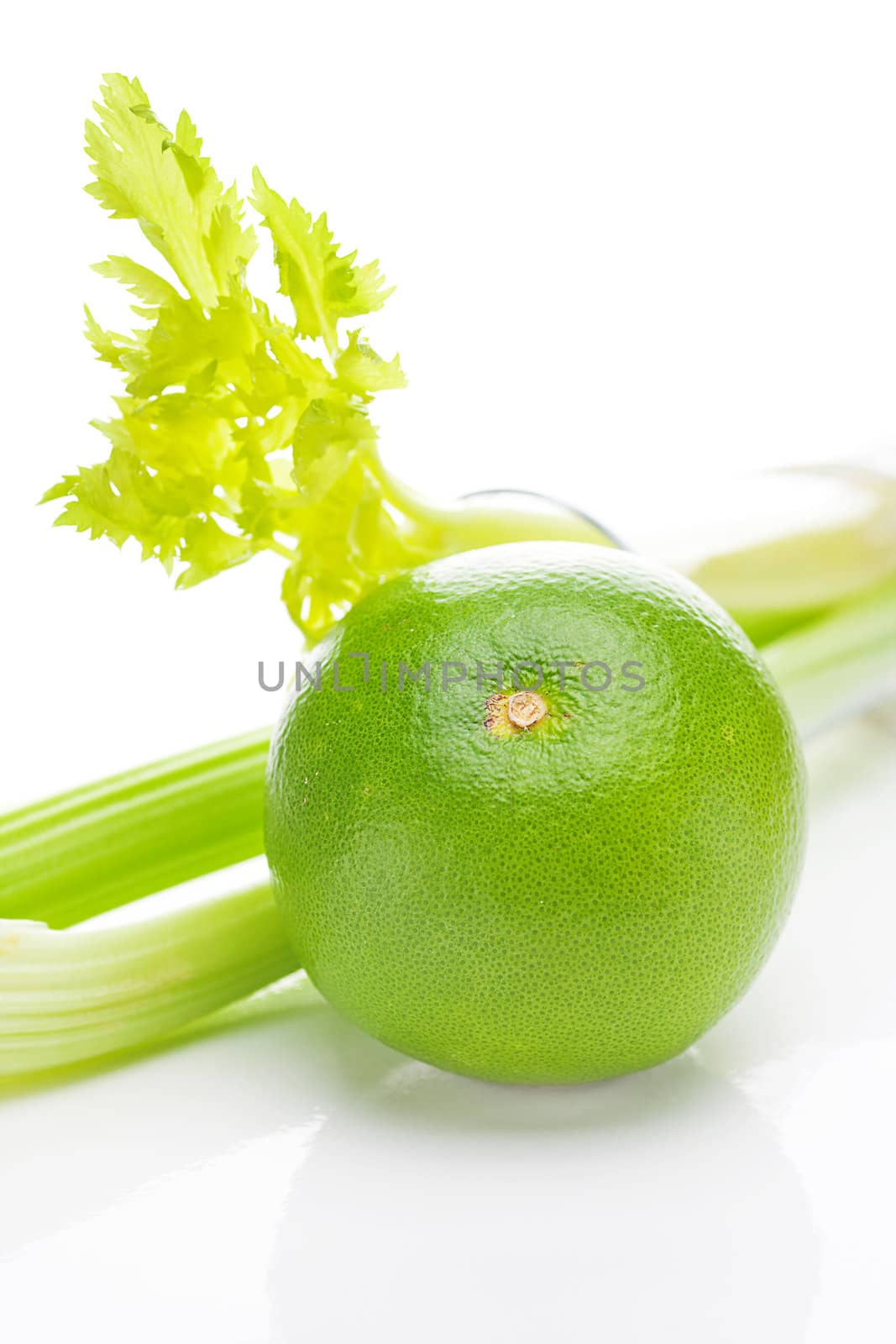 celery in a tall glass, green grapefruit and measure tape isolated on white