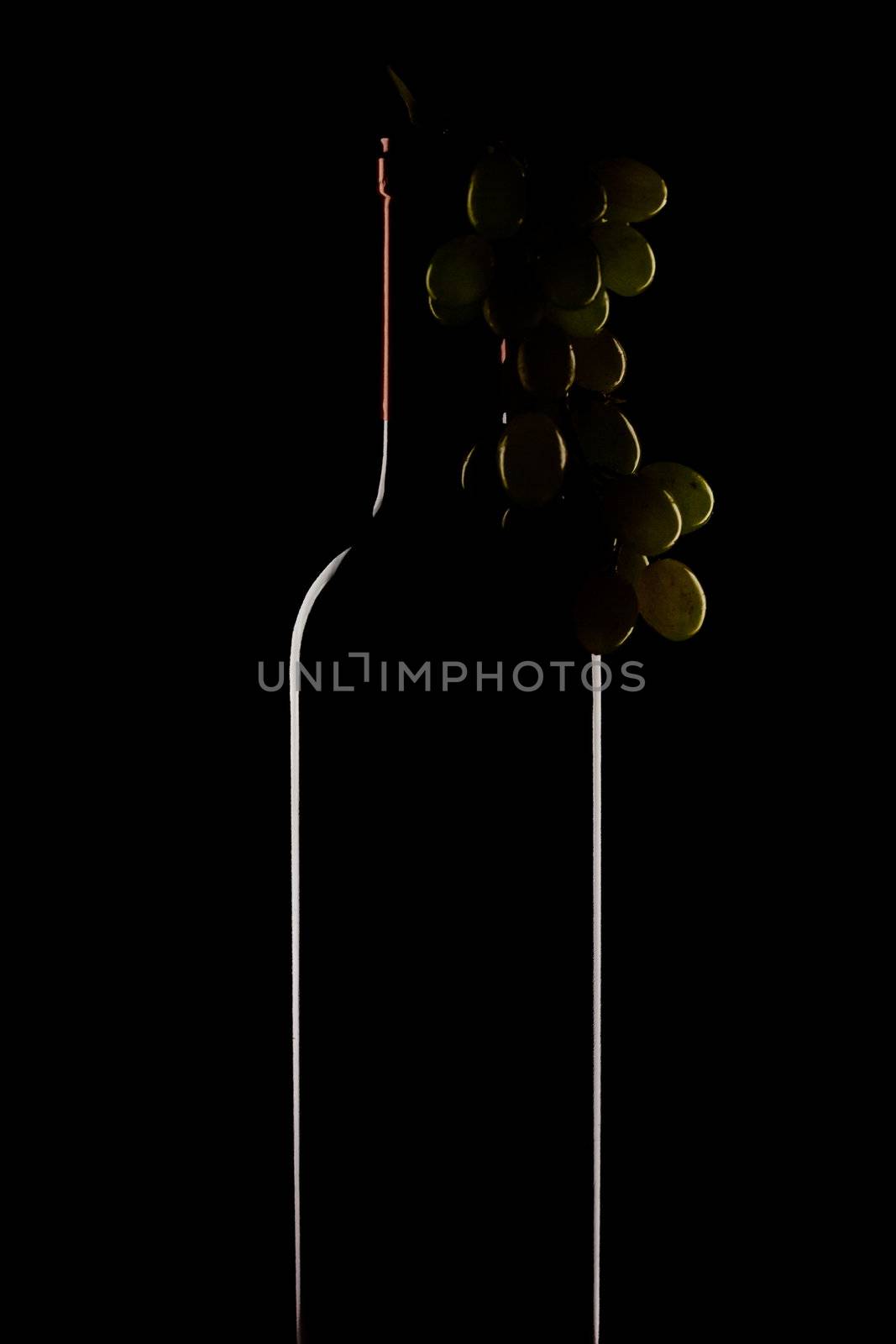 bottle of wine and a bunch of grapes on a black background