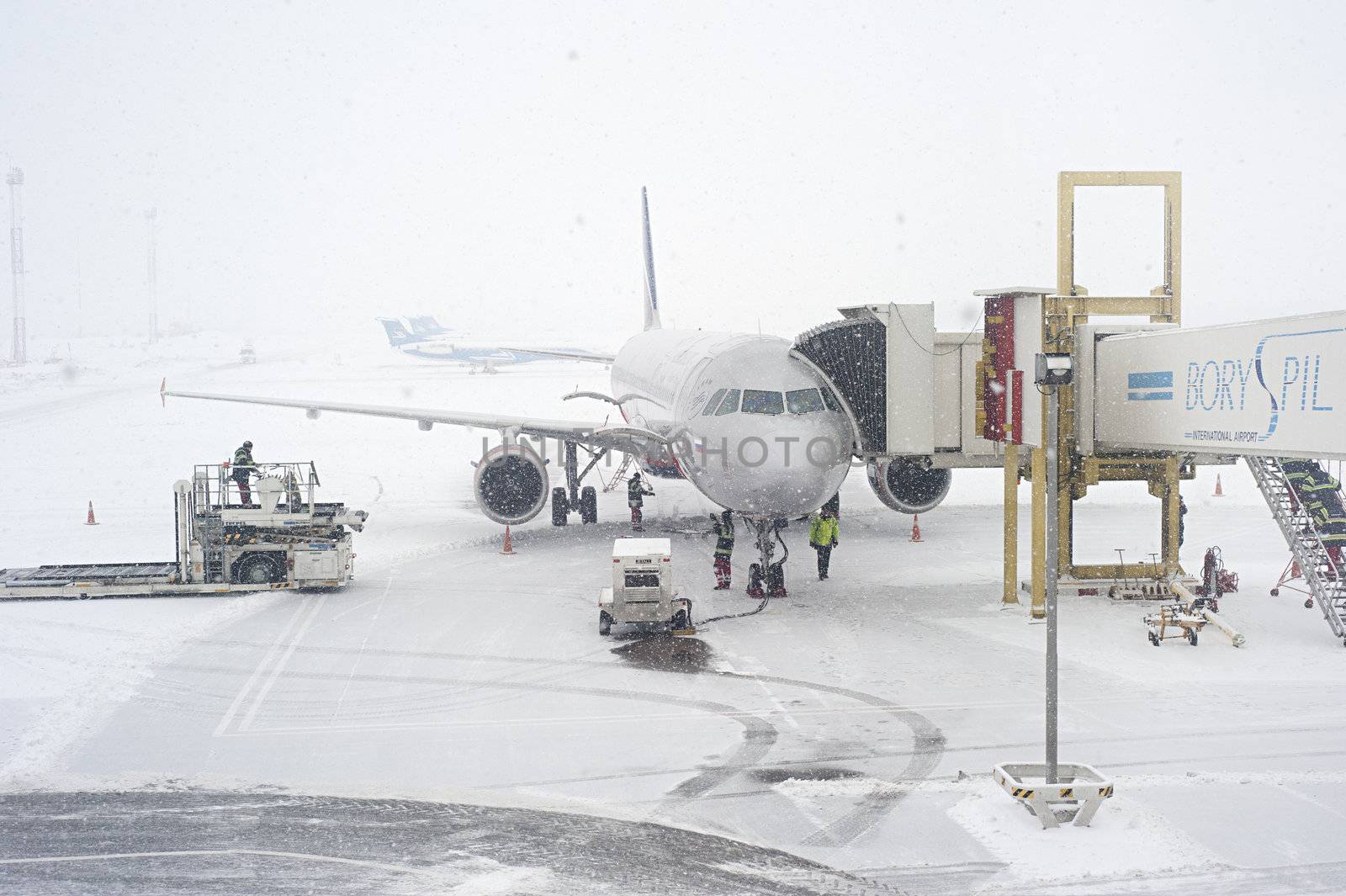 Kiev, Ukraine - January 12, 2013: Unidentified workers prepairing an airplane duirng the snowfall. Kiev was covered by around 20 inches of snow, the largest amount to fall in one weekend since records in 1889