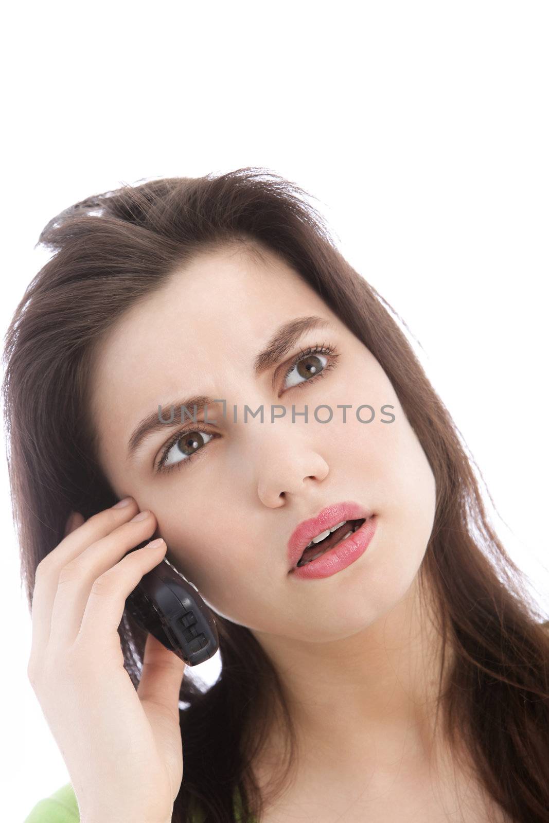 Attractive young woman listening to a call on a mobile phone looking up in consternation as she concentrates on what is being said