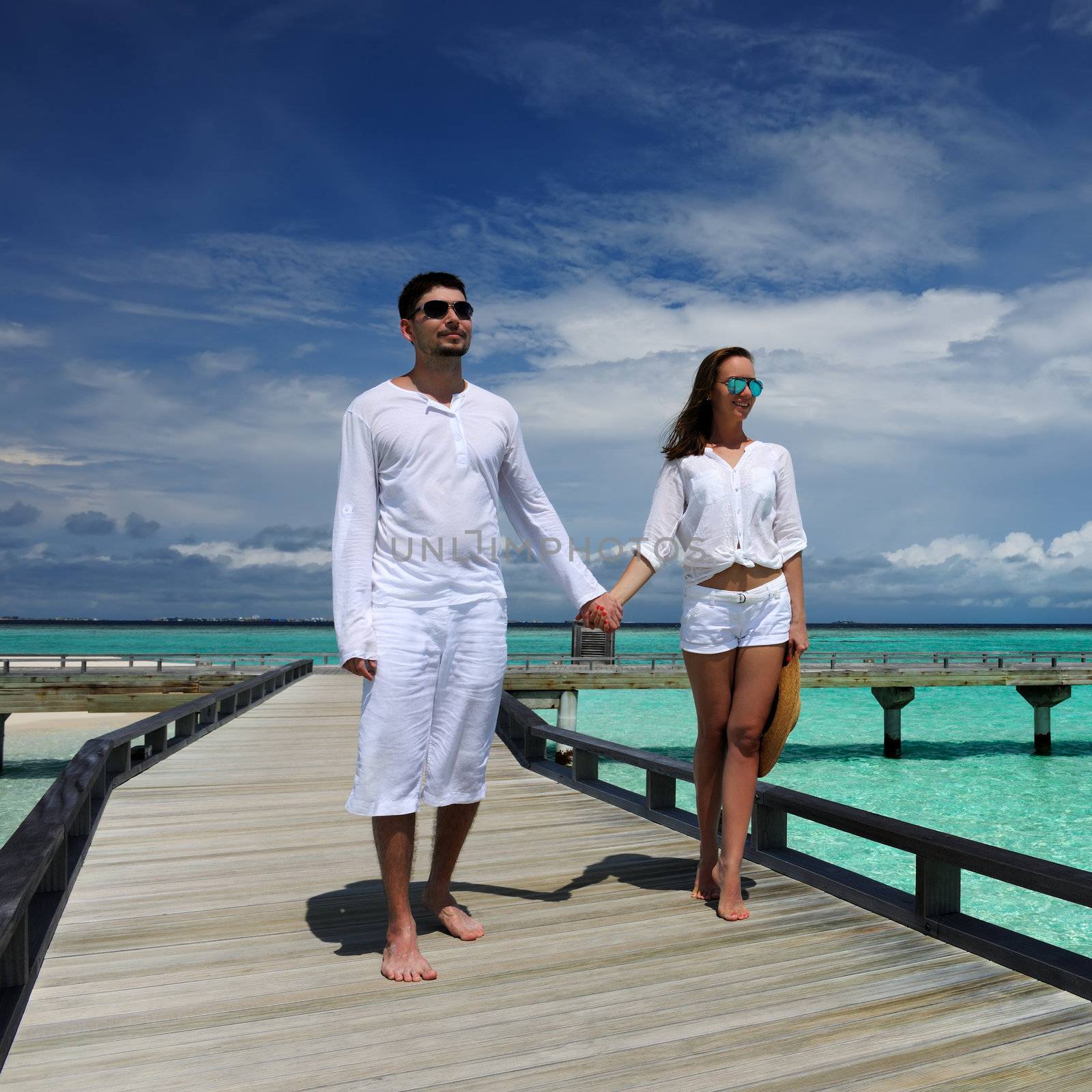 Couple on a beach jetty at Maldives by haveseen