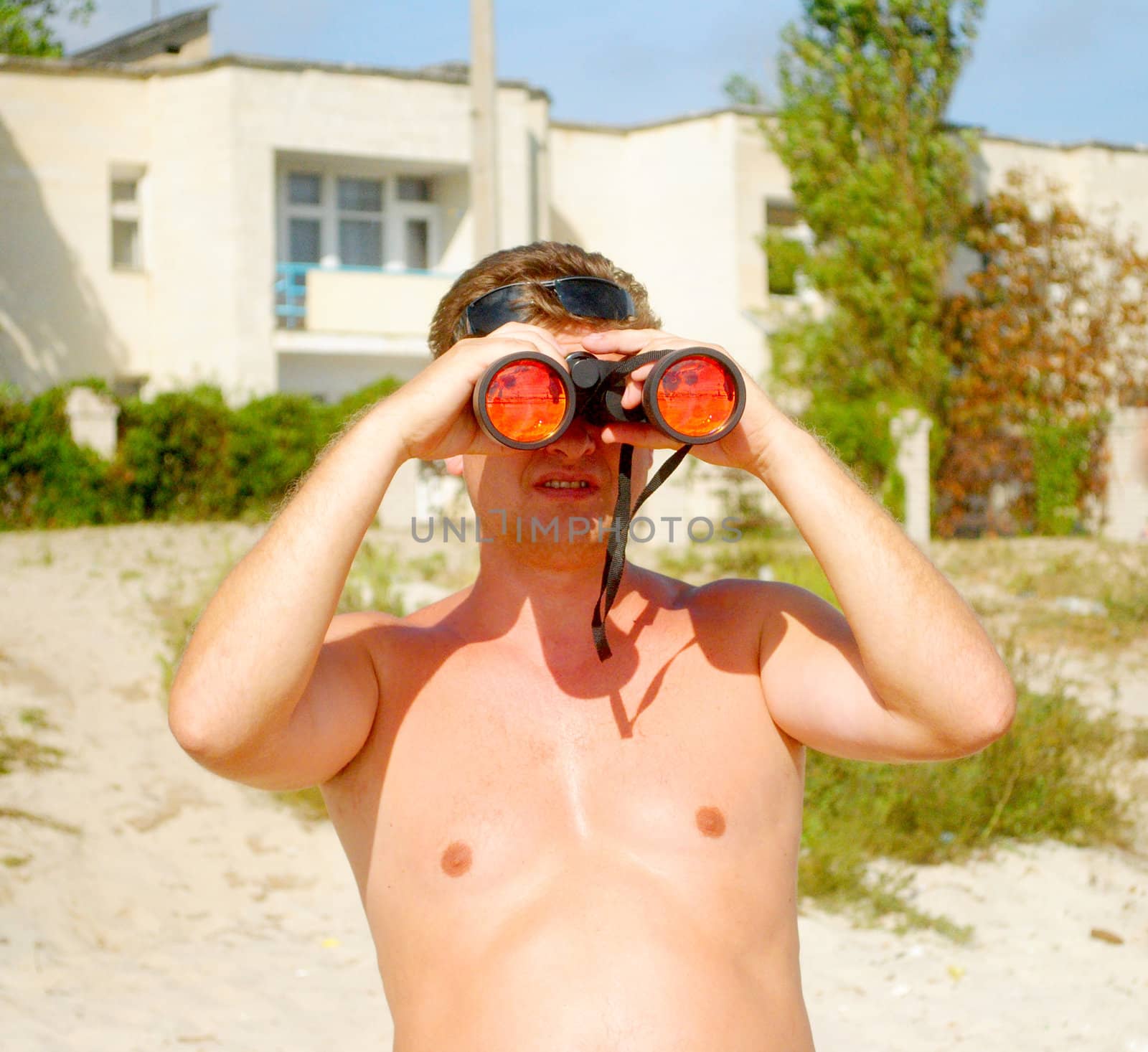 A man with binoculars on the beach by NickNick