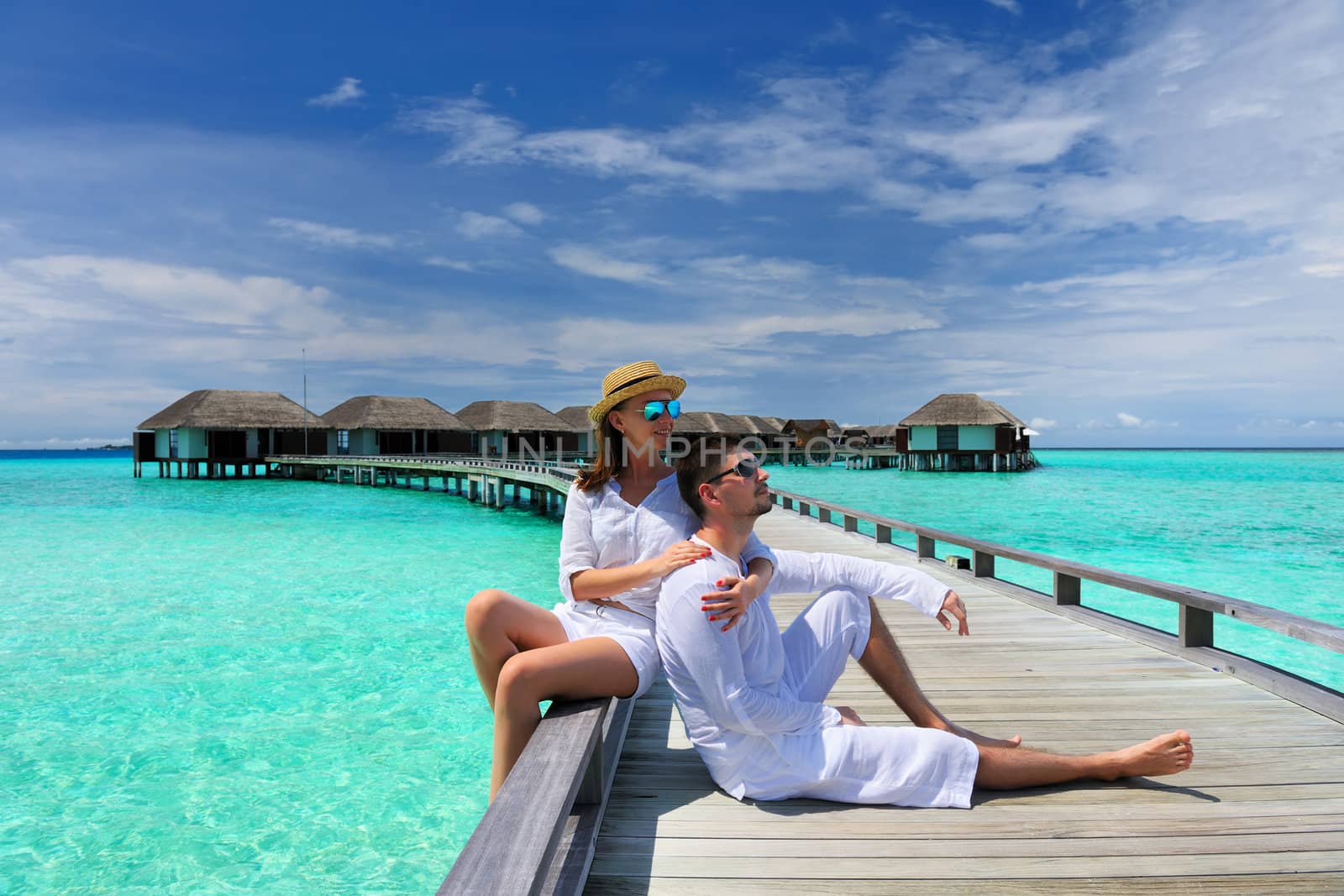Couple on a tropical beach jetty at Maldives
